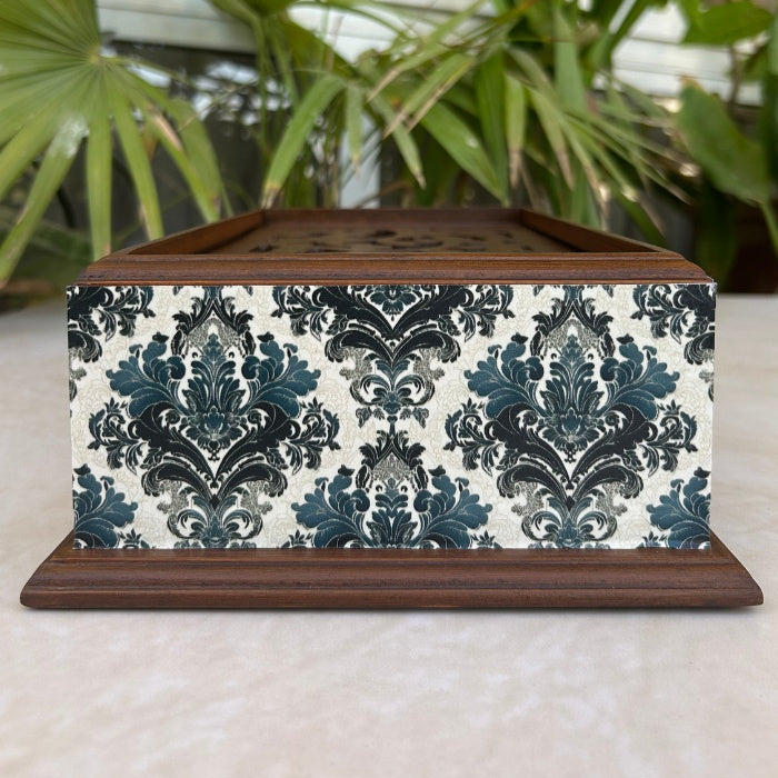 Decorative box with a blue and white pattern on a surface with plants in the background