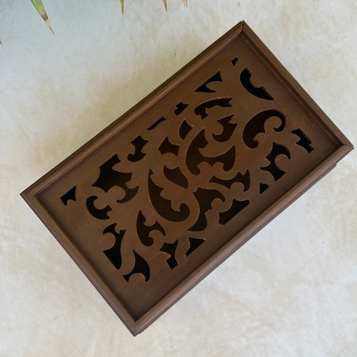 Top view of decorative wooden box with intricate cut-out patterns on a light background