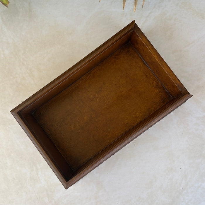 Inside of wooden box on a textured surface with green leaves in the background