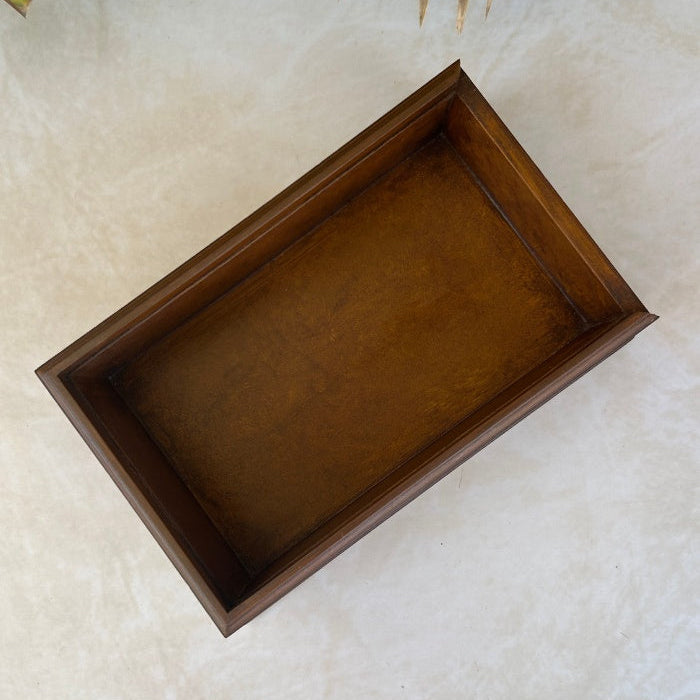 Inside view of wooden box on a textured surface with green leaves in the background