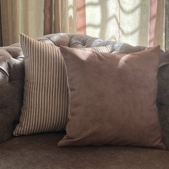 Brown sofa with decorative pillows and a lamp in a room with curtains.