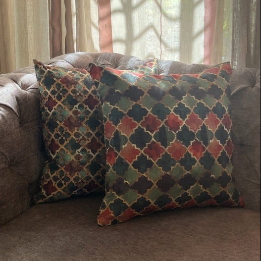 Decorative pillows on a brown sofa with a lamp and curtains in the background
