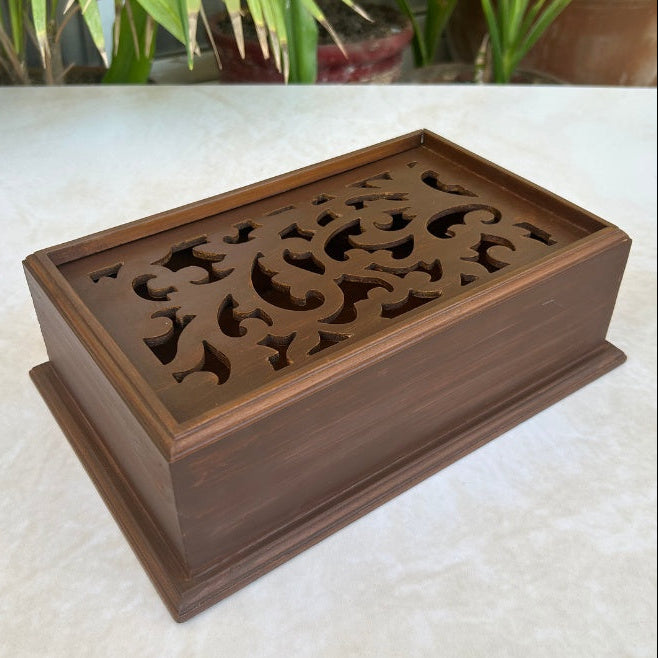 Wooden decorative box with intricate carvings on a light surface