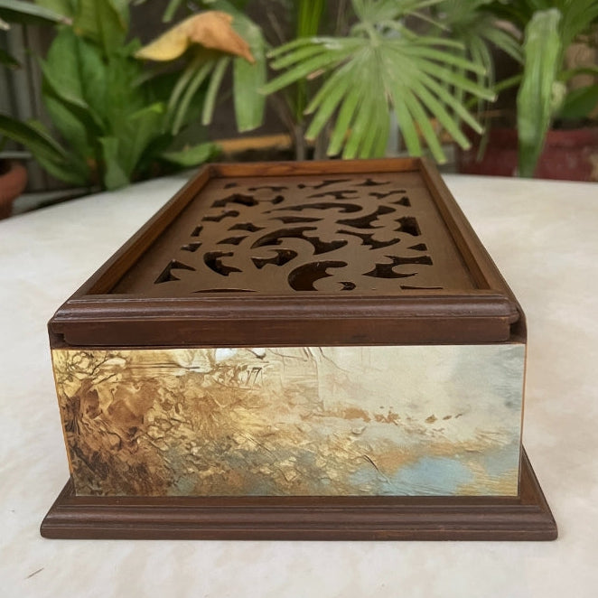 Decorative box with intricate design on a table with plants in the background