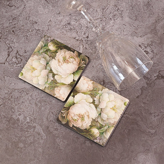 Two square coasters with floral design on a gray surface