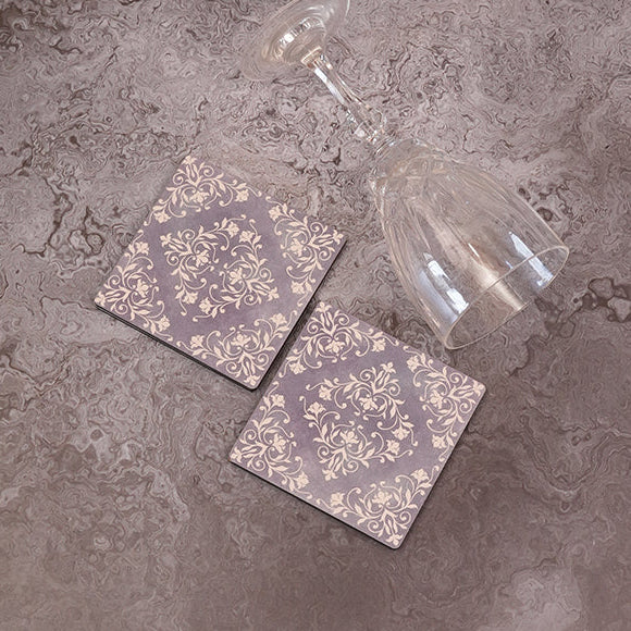Two geometric patterned coasters on a textured surface with a glass of water.