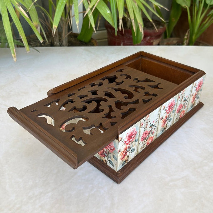 Decorative wooden tray with floral design on a white surface with plants in the background