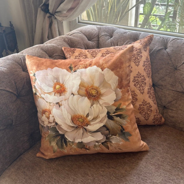 Floral-patterned pillow on a gray sofa with a window and plant in the background