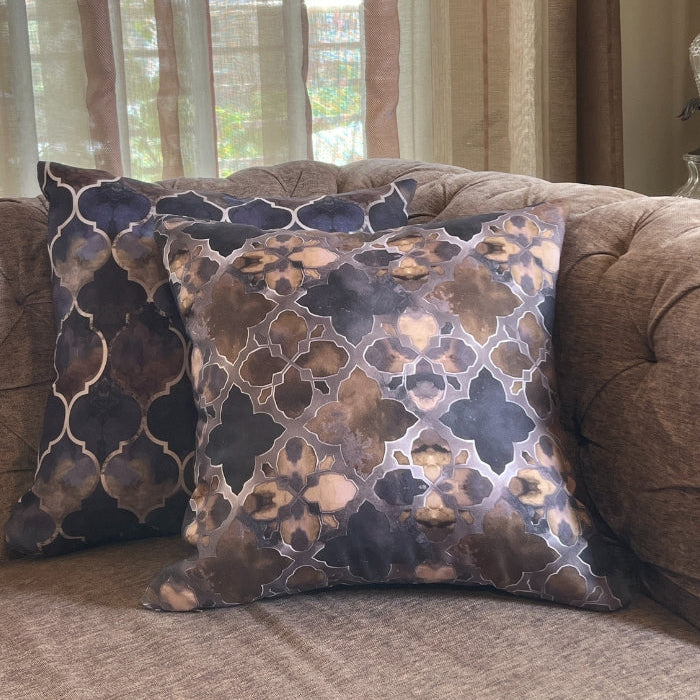 Decorative pillows with a geometric pattern on a brown sofa in a living room setting.