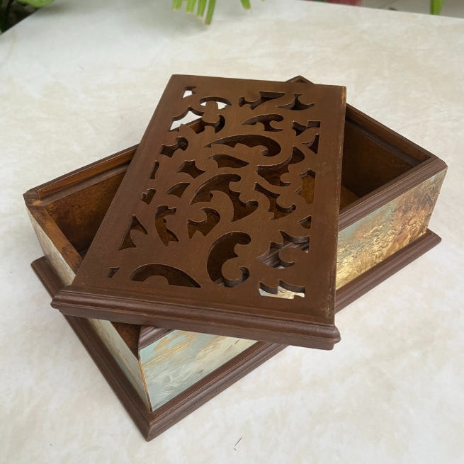 Decorative wooden box with intricate carvings on a light surface